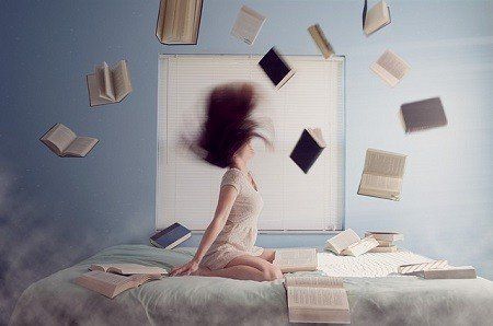 A woman is sitting on a bed with books falling from the ceiling.